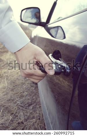 a hand holding a car's remote control pointing to the door.a man opens a machine