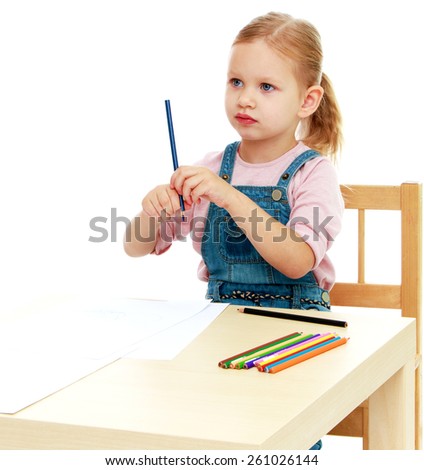 Little girl draws pencils sitting at the table.Childhood education development in the Montessori school concept. Isolated on white background.