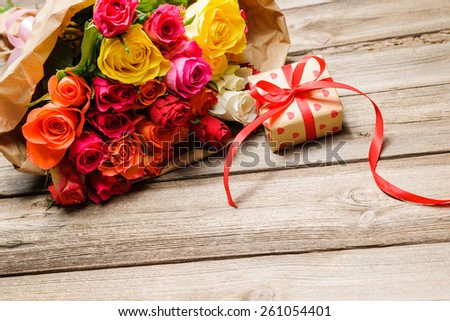 Bunch of roses with a gift box on weathered wooden background