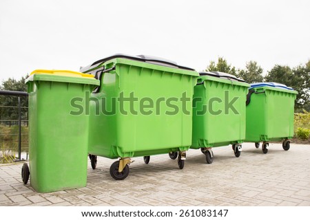 Green garbage containers in a row on stony street Royalty-Free Stock Photo #261083147