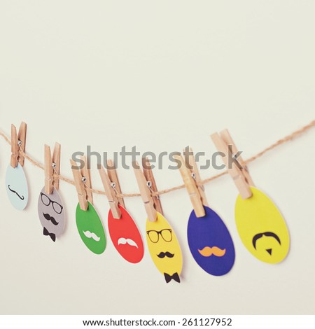 Multicolored hipster styled paper Easter eggs decoration hanging on a rope with clothespin. Square format, instagram look filter applied.