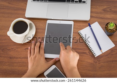 female hands holding a computer tablet on the table in the office