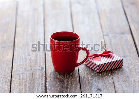 Cup of coffee and gift box on a wooden table.