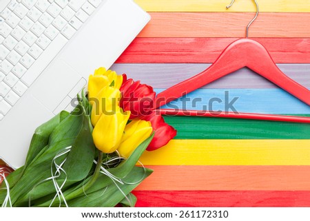 White computer and bouquet of tulips with hanger on multicolor background