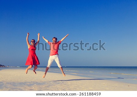 Happy couple jumping on the summer tropical beach