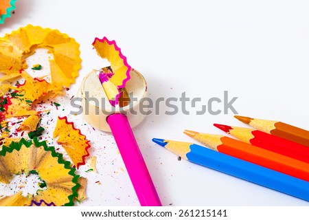 colored pencils, sharpener and shavings on white background with copy space.