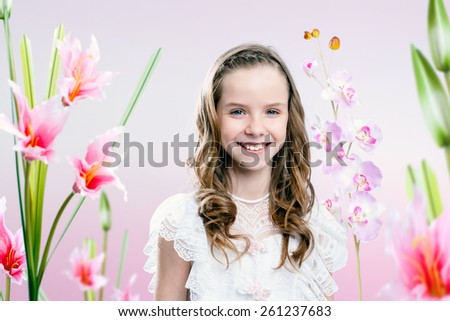 Close up portrait of young girl wearing communion dress in flower garden.