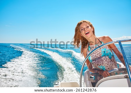 Summer vacation - young woman driving a motor boat  Royalty-Free Stock Photo #261242876