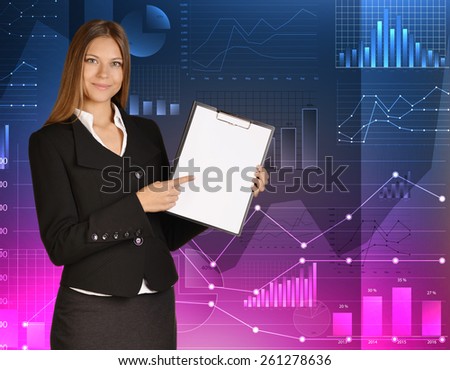 Business woman standing against background of financial charts and holding clipboard.