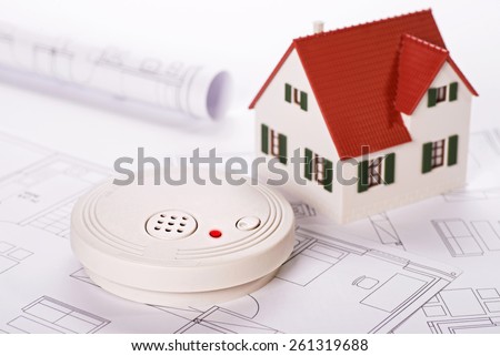 Smoke detector with house and blueprints Royalty-Free Stock Photo #261319688