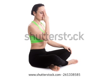 Serene girl practicing yoga nadi shodhana pranayama (Alternate Nostril Breathing), sitting in Easy (Decent, Pleasant Pose), Sukhasana, meditation, copy space