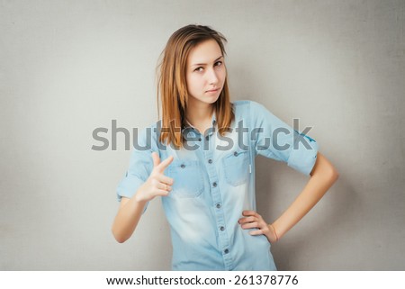 Young girl shows forefinger, attention sign, on grey background