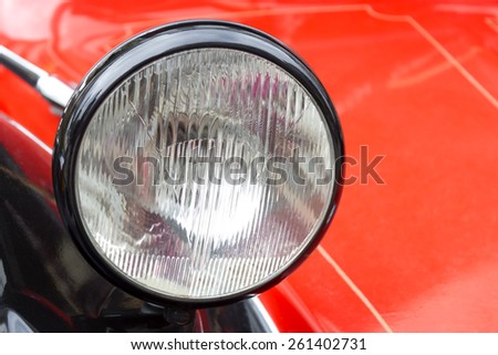 Closeup to a headlight of an old red car. Stock photography.