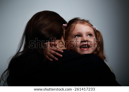 Mother and happy smiling daughter hugging on dark background
