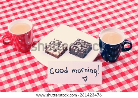Two cups of coffee on the table. Morning coffee and cake. Plate with sweets and a cup of latte. Good Morning. Note Good morning, surprise, a romantic dinner. Cake with icing.