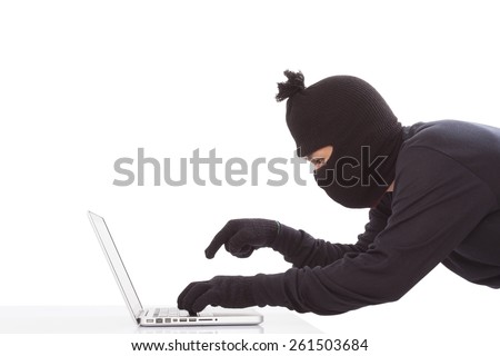 Computer hacker wearing mask stealing data on laptop computer 