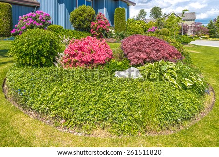 Nicely decorated colorful flowerbed with flowers, stones and bushes as a decorative elements. Landscape design.