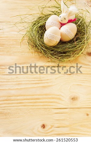 Easter eggs and rabbit in nest on wooden table