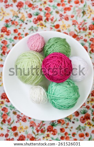 A lot of bright balls of knitting on the background of a red flower