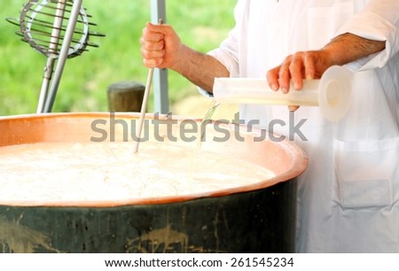 expert Cheesemaker pours milk rennet in copper pot for making cheese in the dairy Royalty-Free Stock Photo #261545234