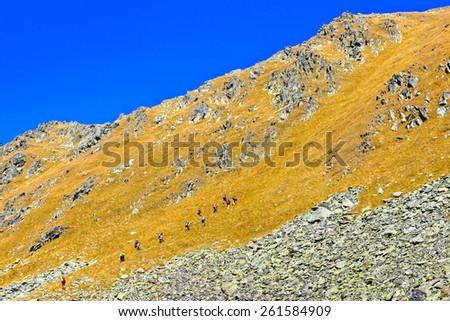 Group of trekking tourists ascent to the mountain pass.Picture was taken during trekking hike in splendid mountains of northern Caucasia, Arhiz region, Abishira-Ahuba range, Karachay-Cherkessia,Russia