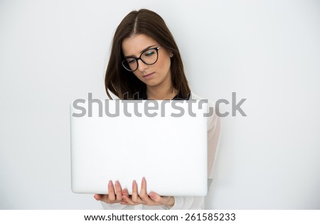 Young beautiful woman standing with laptop over gray background
