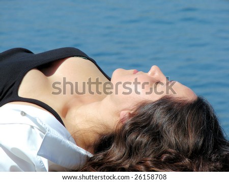  young beautiful woman laying and having a rest on quay of mediterranean sea, spain
