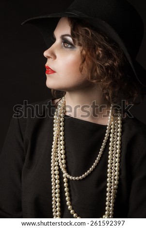 Portrait of young beauty dark hair girl in vintage chanel 1920 style in black hat 