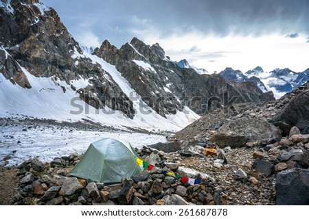 Lonely mountaineers camp in very high snowy moutains beside glacier. Picture was taken during a trekking hike in the amazing and stunning Caucasus mountains, Bezengi region, Kabardino-Balkaria, Russia