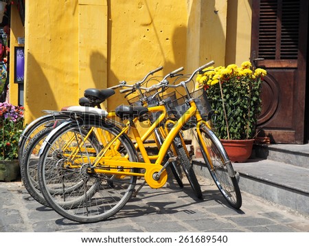 Various yellow bikes for rent in a row parked near yellow wall        