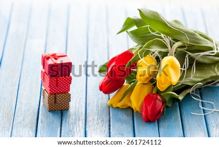 Gift boxes and bouquet of tulips on blue background.