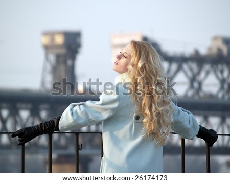 Beautiful blonde lady in overcoat on promenade