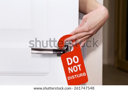 Hand sign do not disturb put on the room doors Royalty-Free Stock Photo #261747548