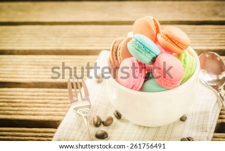 Macarons in a cup of tea on wooden tabel with vintage pastel retro tone soft focus.