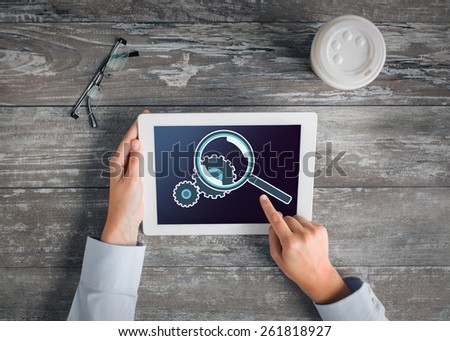 business, people, setting and technology concept - close up of hands pointing finger to tablet pc computer screen showing magnifier and cogwheel, coffee cup and eyeglasses on table