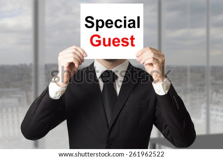 businessman in suit hiding face behind sign special guest