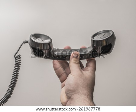 brutal man Hand with black plastic old retro vintage new telephone handset isolated on gray background Empty space for inscription or objects