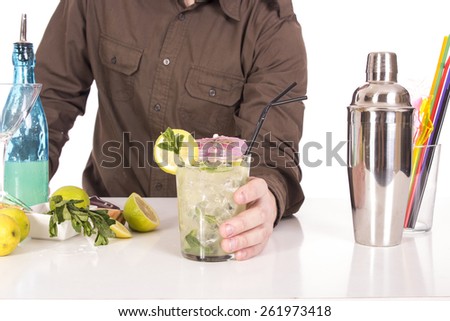 Bartender preparing mojito cocktail drink, with limes, ice and brown sugar