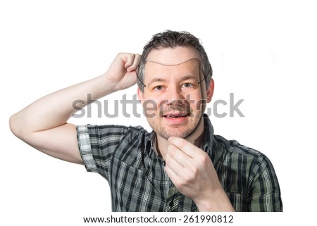 Picture of a man putting on a mask of himself.