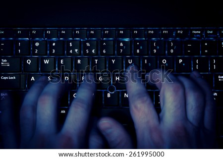 hands typing on keyboard in blue light with motion blur Royalty-Free Stock Photo #261995000