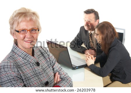 Businesswoman in office environment. Three people with focus on mature woman in front. Isolated over white.
