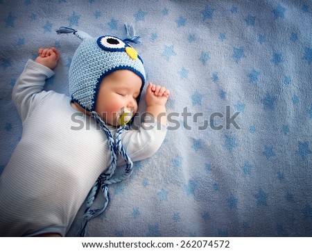 4 month old baby in owl hat sleeping on blue blanket Royalty-Free Stock Photo #262074572
