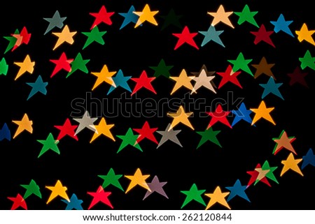 Star shaped qustom bokeh created from decoration lights and isolated on black background.