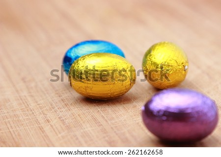 small chocolate eggs over wooden background