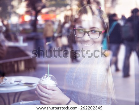 Young blonde girl drinking coffee in cafe.