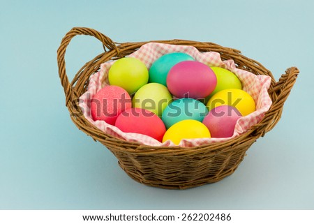 Happy Easter concept. Wicker basket full of colorful painted eggs on blue background