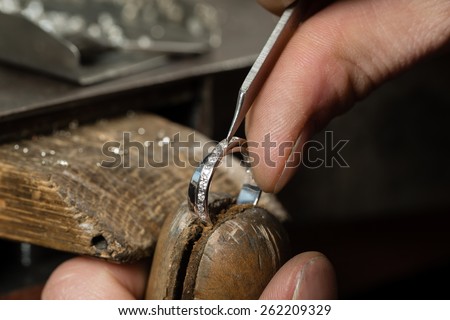 Craft jewelery making.  Repairing ring by inlaid tight gem. Royalty-Free Stock Photo #262209329
