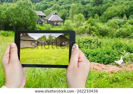 travel concept - tourist takes picture of backyard in peasant household in russian village on smartphone, Smolensk region
