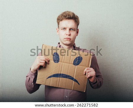 man, holding a picture of a sad smiley