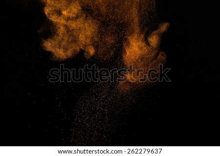 Abstract orange powder explosion on black background.